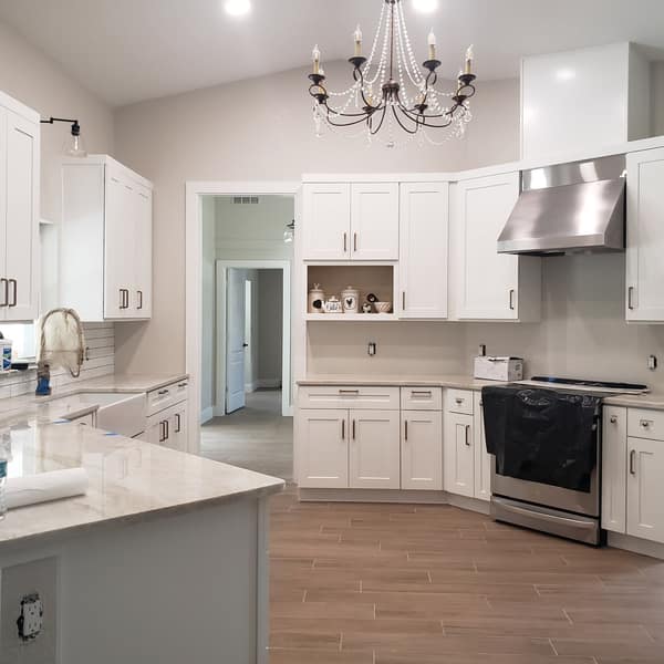 White kitchen with a wood-look plank tile floor and a subway tile backsplash