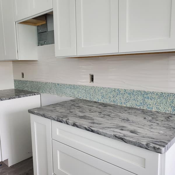 Glass mosaic backsplash above a granite countertop