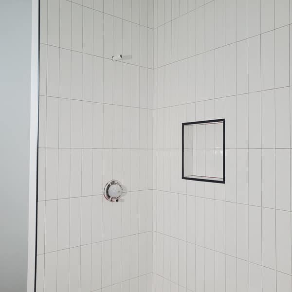 Shower with white vertically stacked wall tile and a recessed niche