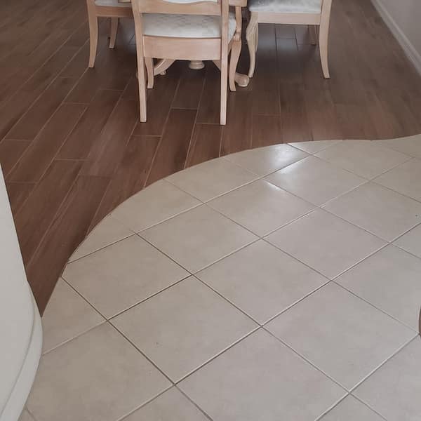 Large-format tile floor meeting a curved wood floor in a dining area