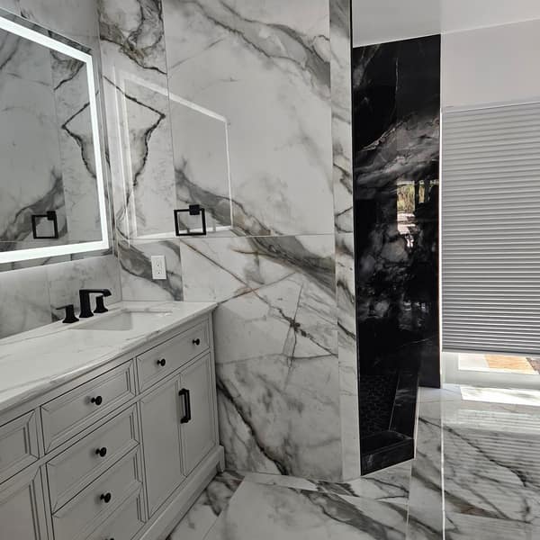 Primary bathroom with large-format white marble-look porcelain tile on the walls and floor