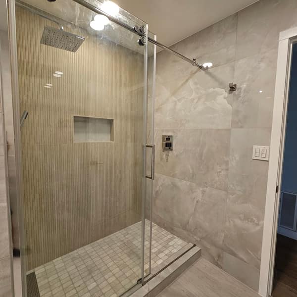 Shower with a fluted wood-look feature wall, onyx-look porcelain tile and a sliding glass door
