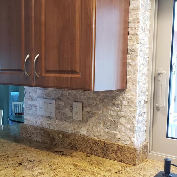 Stacked-stone backsplash beneath wood kitchen cabinets